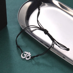 Detail of a black braided bracelet featuring a silver Yoga OM symbol on a metallic tray