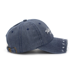 Detail of washed denim baseball cap with white Take embroidery and distressed frayed edges