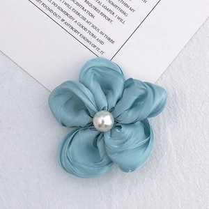 Handmade blue fabric flower accessory with pearl center on decorative card background