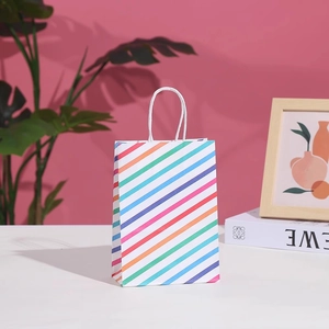 Colorful striped paper gift bag with white handles on a clean minimalist tabletop