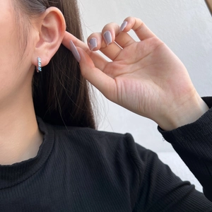 Detail of S925 sterling silver hoop earring with light blue heart zircon on ear