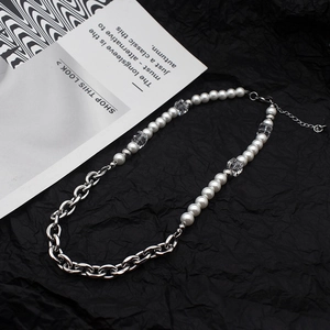 Detailed view of pearl and silver chain necklace with faceted beads on black background