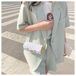 Close-up of a white quilted cylinder bag with gold chain strap on a stylish model
