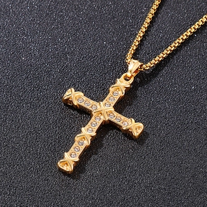 Close-up of golden titanium steel cross pendant with sparkling inlaid rhinestones