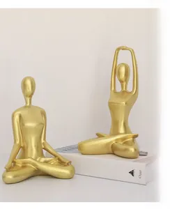 Close-up of dual golden yoga figure ornaments set on book for minimalist home decor