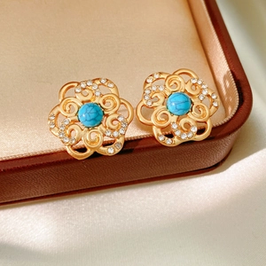 Detailed close-up of golden floral stud earrings with turquoise and clear crystals