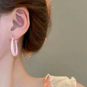 Close-up of a pink oval hoop earring with a smooth glossy finish worn by a model