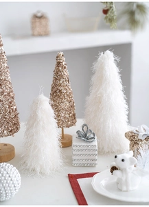 Detailed close-up of champagne cone tree ornaments and plush white Christmas desk decor