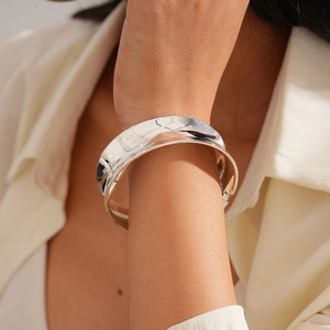Close-up of a wide polished silver metal cuff bracelet on a woman wrist with high shine