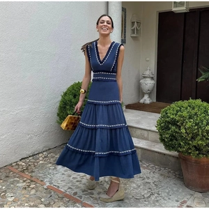 Détail de broderie géométrique blanche sur robe longue à volants bleu marine sans manches