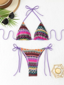 Bohemian geometric wave pattern bikini set with lilac ties on white beach towel background