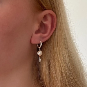 Detail of S925 silver twist hoop earrings with pearl and star pendant on ear