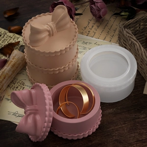 Detail of round silicone mold with finished bow-embossed jewelry boxes on vintage paper