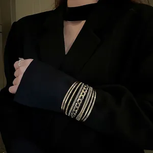 Layered gold geometric open bangles set featuring Cuban chain and multi-ring metal design