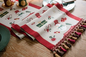 Detail of Christmas table runner with festive jacquard patterns and red-green tassels
