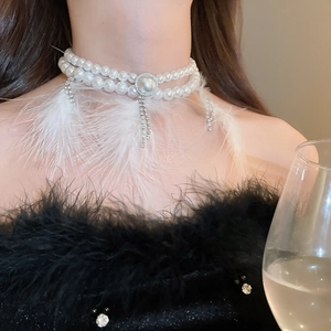 Detail showing white pearl choker with rhinestone tassels and soft feather accents on model