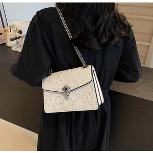 Detailed view of white snake-textured crossbody bag with silver chain strap and metal clasp