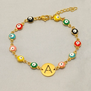 Detailed macro view of gold chain bracelet with colorful evil eye beads and letter A charm