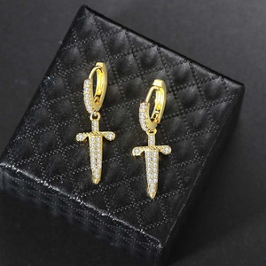 Macro shot of gold dagger hoop earrings with sparkling zircon stones on a black jewelry box