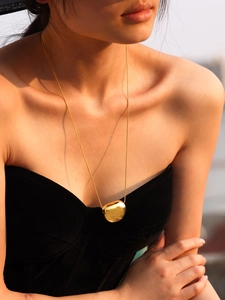 Polished 18k gold plated stainless steel bean pendant necklace on model in golden hour