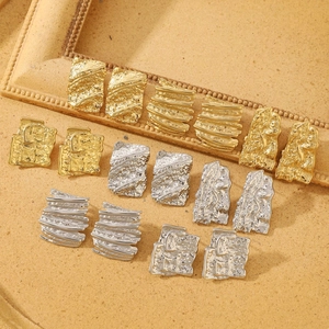 Detailed view of hammered irregular square earrings in gold and silver stainless steel