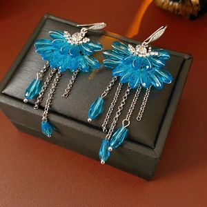 Détail de boucles d'oreilles fleurs bleues avec pampilles et zircons sur boîte