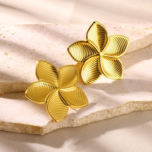 Elegant gold plumeria flower stud earrings with radial texture on a stone pedestal