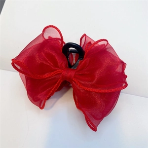Close-up of a red organza bow hair claw clip with mesh texture and plastic grip