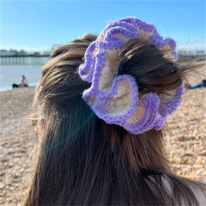 Detailed shot of a purple ruffled crochet hair scrunchie styled on long dark hair at the beach