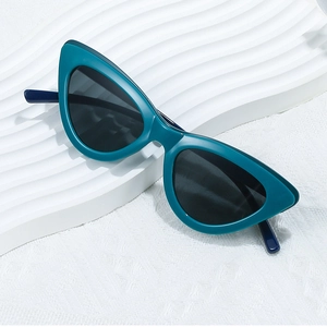 Dettaglio di occhiali da sole retrò cat-eye con montatura verde scuro su fondo bianco