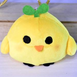 Close-up of a cute yellow plush chick pendant with a green sprout on its head.
