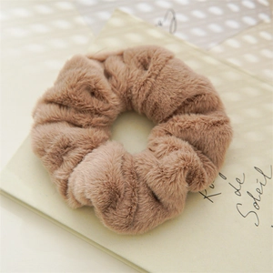 Close-up of soft brown plush scrunchie on vintage paper background with elegant texture