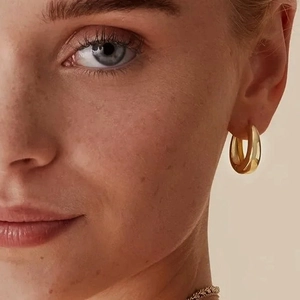 Primo piano di una modella che indossa orecchini a cerchio dorati in acciaio inossidabile