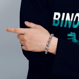 Close-up of a silver stainless steel thick link chain bracelet worn on a person's wrist