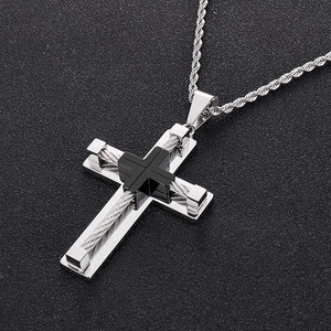 Macro shot of a two-tone silver and black stainless steel cross pendant on a rope chain