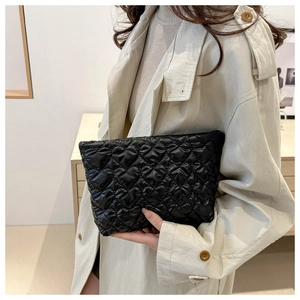 Close-up of black quilted clutch bag with heart-shaped stitching and glossy fabric