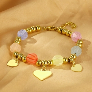 Detail of colorful pumpkin beads and gold heart pendants on a titanium steel bracelet