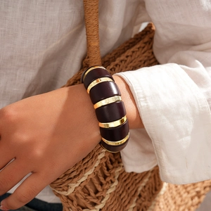 Detailed view of chunky brown resin segments with golden metal rings on a stretch bracelet