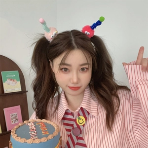 Cute plush monster hair clip with googly eyes and colorful antennas on a girl