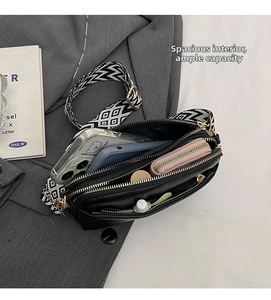 Detail view of black faux leather crossbody bag with spacious multi-layer interior storage