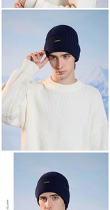 Close-up of a men's navy blue ribbed knit beanie with a studio leather tag detail