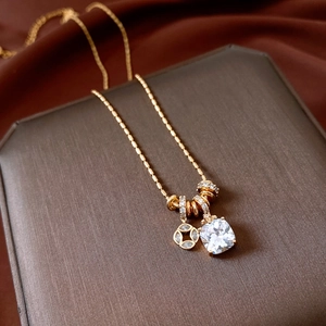 Detail of 18k gold plated necklace with square zircon pendant on silk background