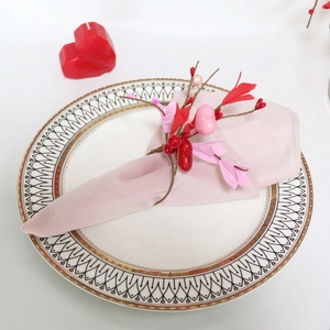 Detail of pink napkin ring with red berries and heart decor on geometric ceramic plate