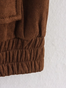 Nahaufnahme der dunkelbraunen Wildlederjacke mit elastischen Bündchen und Nahtdetails