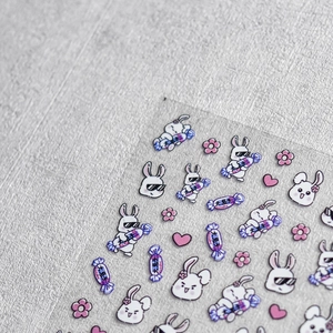 Macro-opname van nail art stickers met reliëf van konijnen en snoepjes op grijze stof