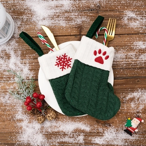 Close-up of green knitted Christmas cutlery holders with snowflake and paw embroidery