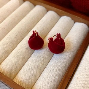 Vue macro des boucles d'oreilles dorées 14k avec clous en velours rouge bordeaux