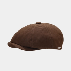 Close-up of brown newsboy cap canvas fabric and white embroidered letters DYX on side