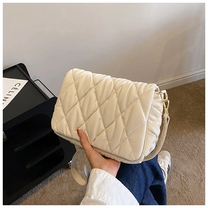 Detail of quilted cotton crossbody bag in beige with elegant gold chain strap and texture