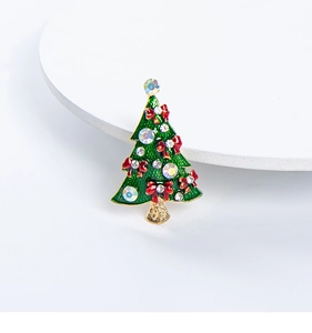 Close-up of a Christmas tree brooch with green enamel, red bow and crystal rhinestones